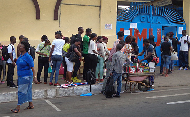 United Methodist University students line up before the school gates for a temperature check and hand- washing in Monrovia, Liberia. Those precautions are in place because of Ebola. Photo by Julu Swen, UMNS
