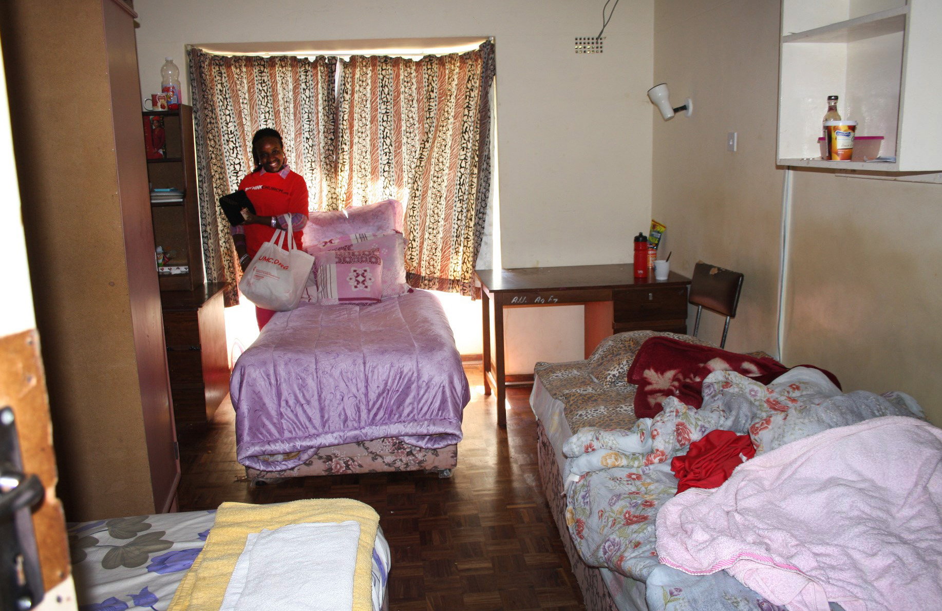 Three beds are visible in Tapiwawashe Muganyura's room in one of the women's residence halls at Africa University. The board of directors encouraged Vice Chancellor Munashe Furusa to come up with a plan to renovate the aging buildings and build new ones. Photo by Vicki Brown, UMNS
