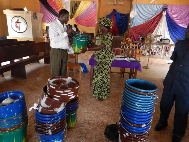 The Rev. Winston Ashcroft distributes hand-washing buckets to Rev Mariama Bockarie for the Makeni District.