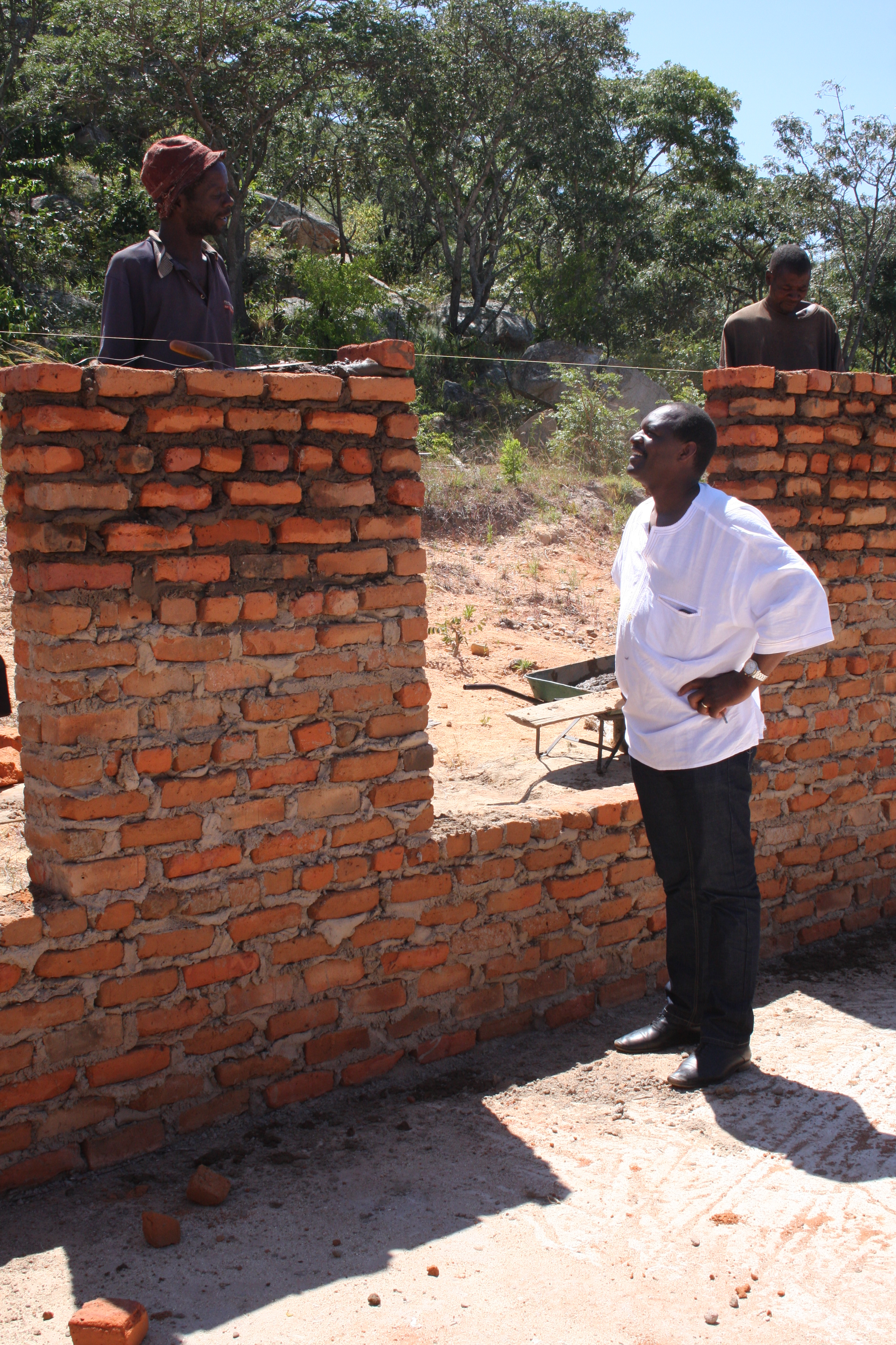 The Rev. Lloyd Nyarota chats with a mason who is building walls for the new classrooms at Saungweme Primary School. Photo by Vicki Brown, UMNS