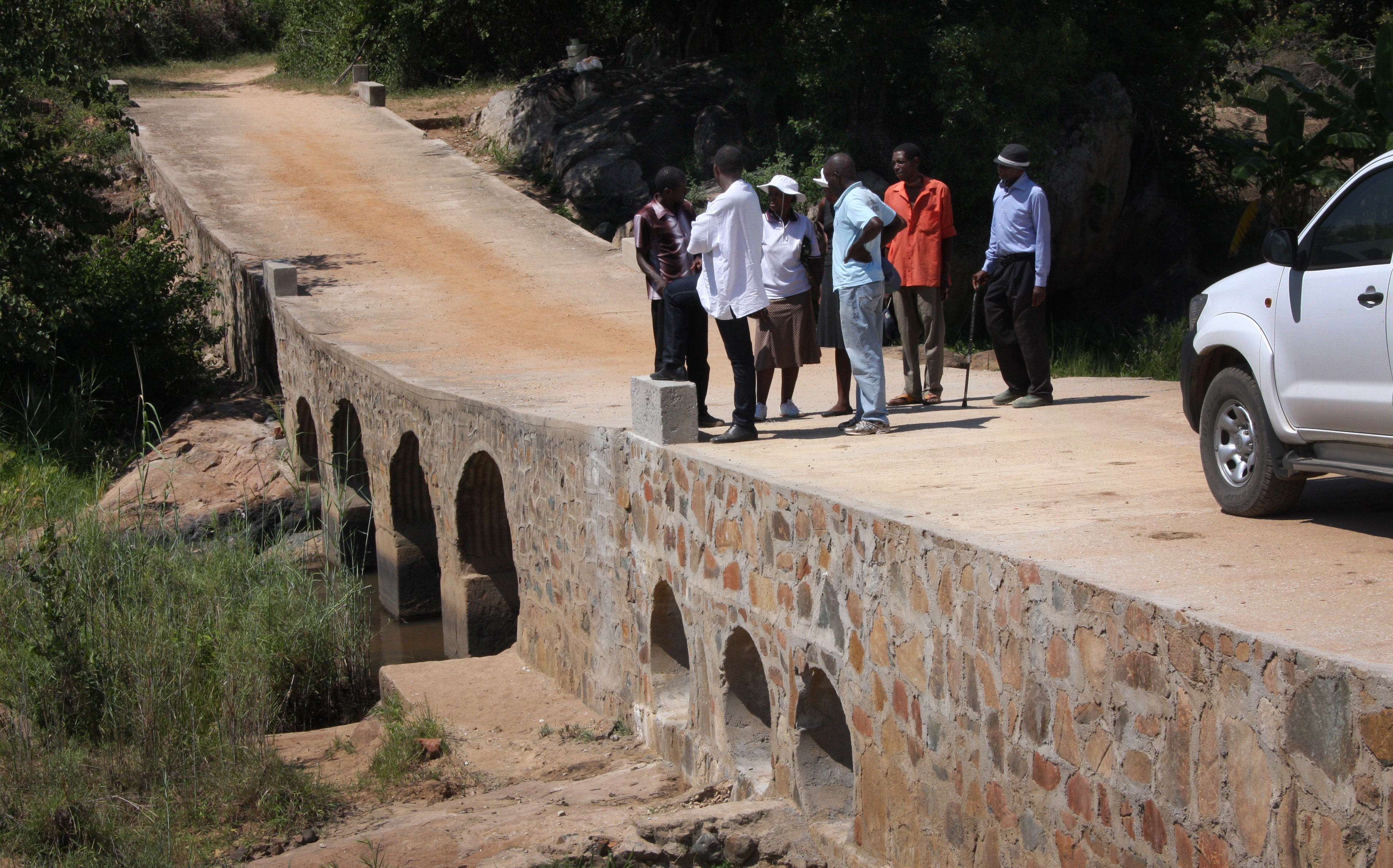 Residents who worked on rebuilding a bridge in the Chitora community discuss finishing touches such as guardrails and controlling bank erosion. Photo by Vicki Brown, UMNS