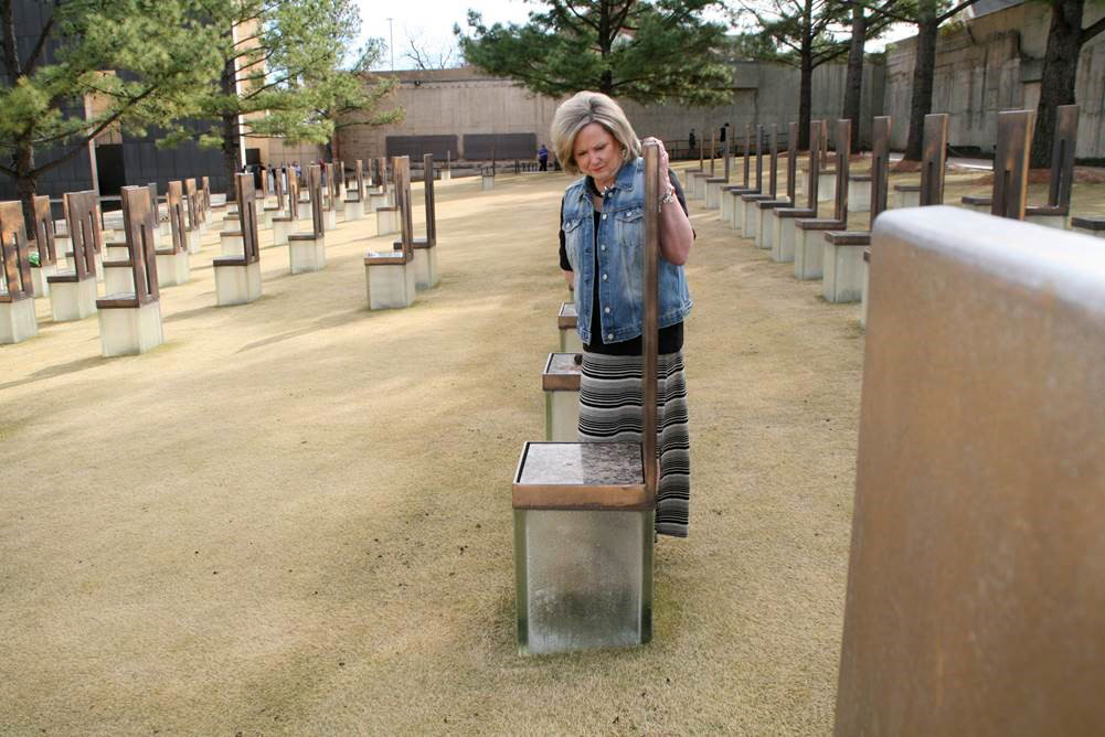 The “Field of Empty Chairs” at the Oklahoma City National Memorial and Museum marks the footprint of the Alfred P. Murrah Federal Building. Each of the 168 translucent chairs represents a person killed in the bombing. Ruth Schwab stands at the chair that represents one of her best friends, Patricia Nix. Photo by Boyce A. Bowdon, UMNS