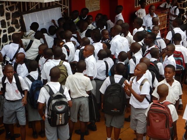 Students at the Albert Academy pour over one another  - ignoring the ABC (Avoid Body Contact) of Ebola - to identify their classes displayed on the notice board.