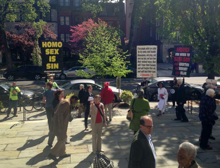 Protesters carry signs outside Foundry United Methodist Church on April 26.