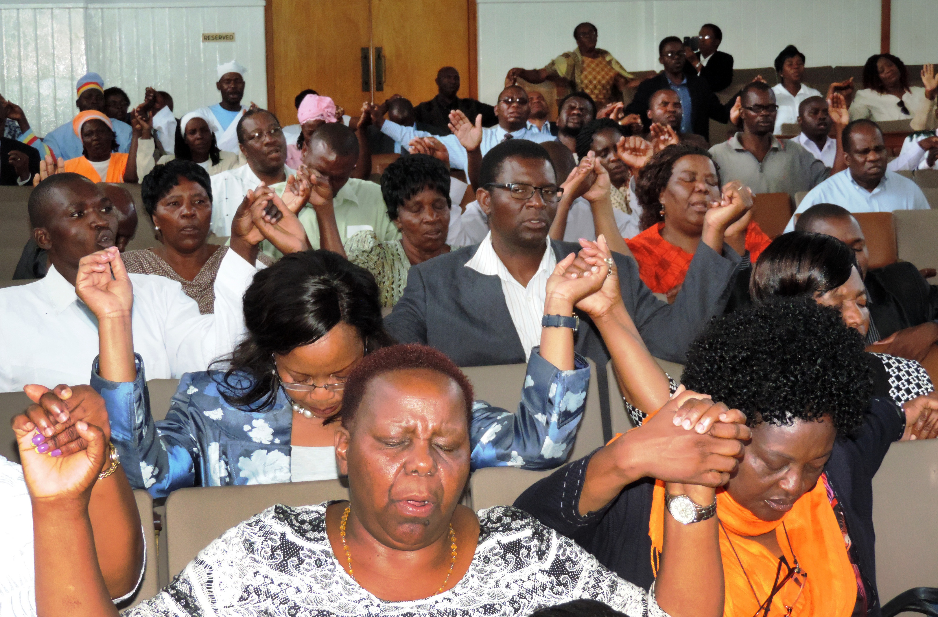 Worshippers at Harare’s Trinity Methodist Church unite hands in prayer at prayer meeting about xenophobia in South Africa. Photo by Taurai Emmanuel Maforo, UMNS
