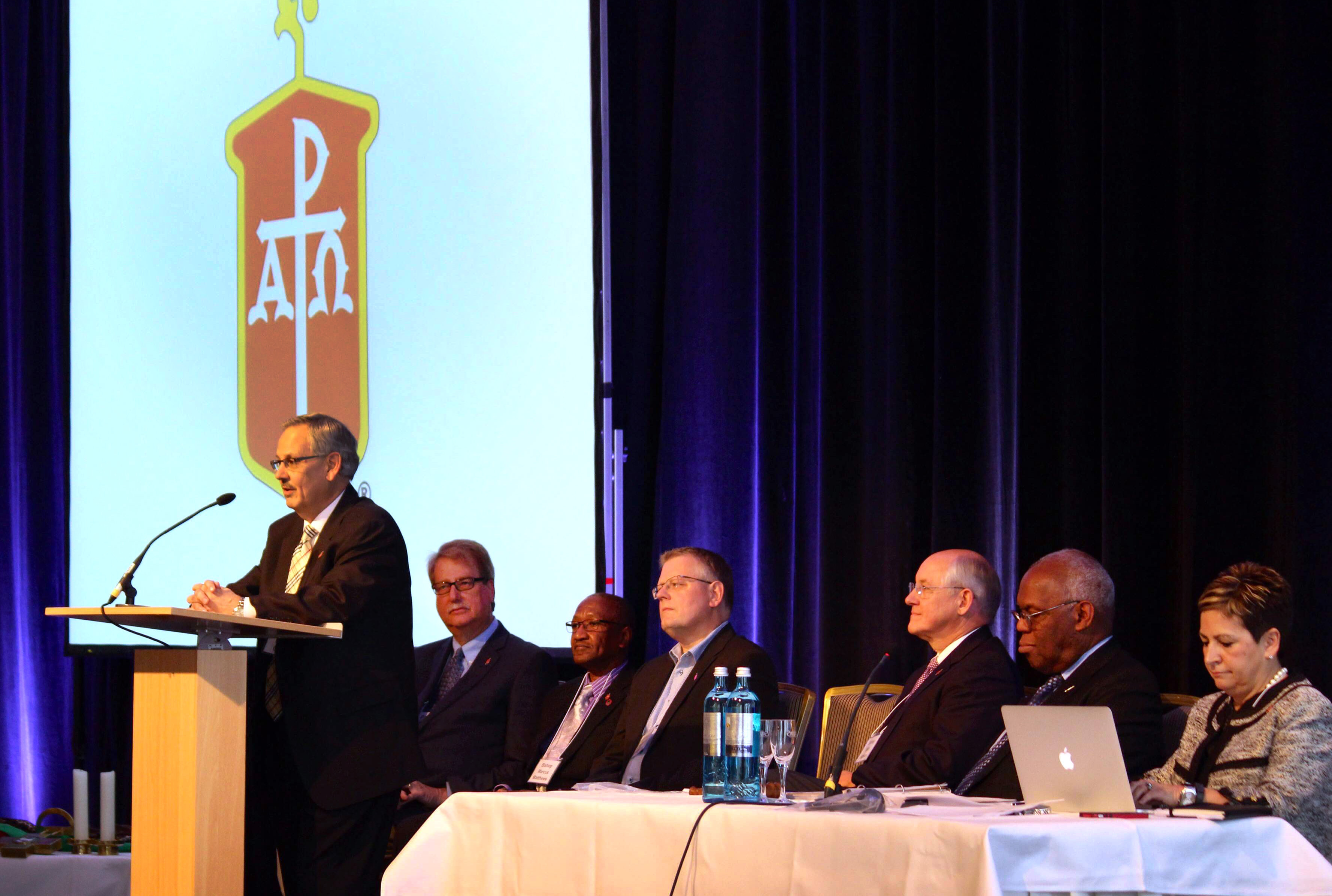Bishop Bruce Ough speaks, as from left, Bishops Kenneth H. Carter, Marcus Matthews, Christian Alsted, Michael Watson,  Warner Brown and Cynthia Fierro Harvey listen during the May 2015 meeting in Berlin. Dakotas-Minnesota Area Bishop Ough, was elected next president of the Council of Bishops. Photo by Kay Panovec, United Methodist Communications