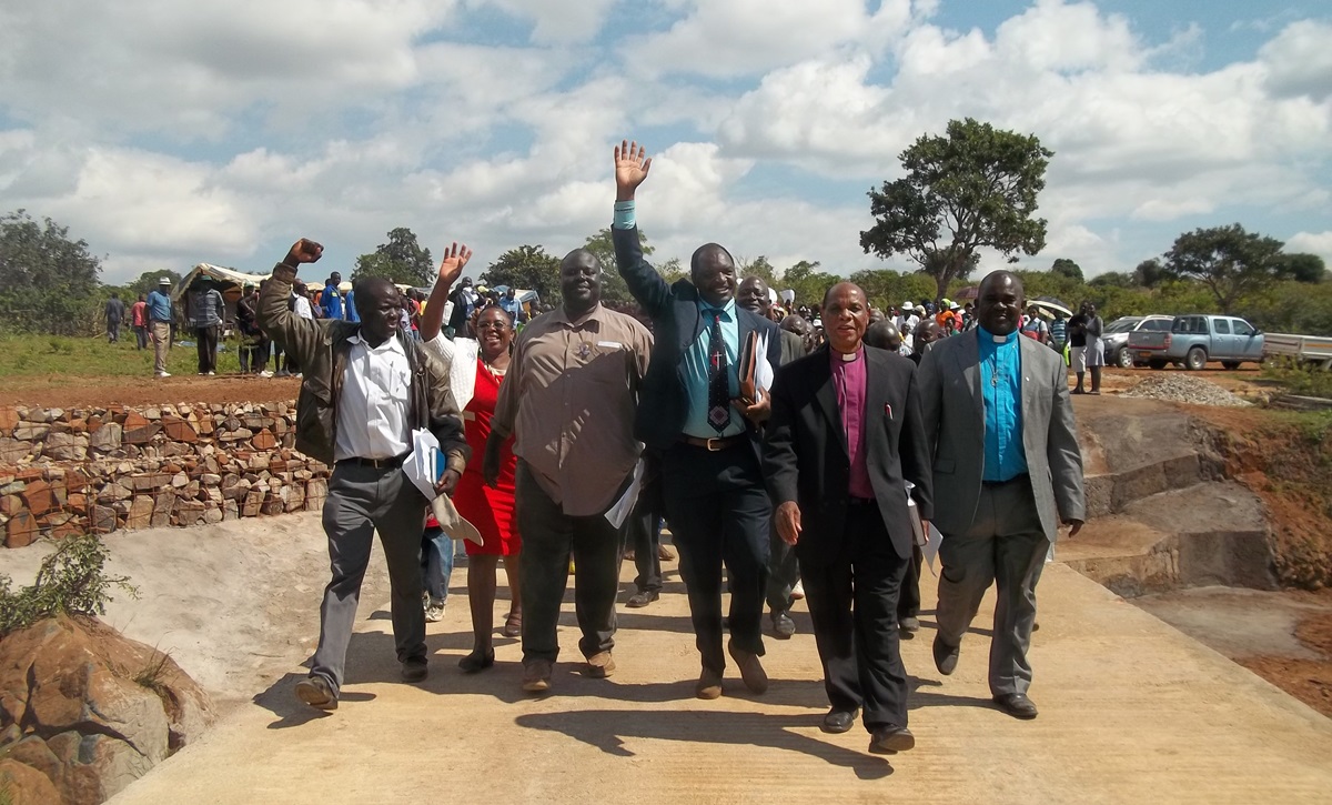 Bishop Eben K. Nhiwatiwa leads the congregation across the new Chitora-Gwarada Bridge. Raising his hand in the center is the Rev. Lloyd Nyarota. In the blue clerical shirt is the Rev. Daniel Chitsiku, Mutare district superintendent. Photo by Taurai Emmanuel Maforo