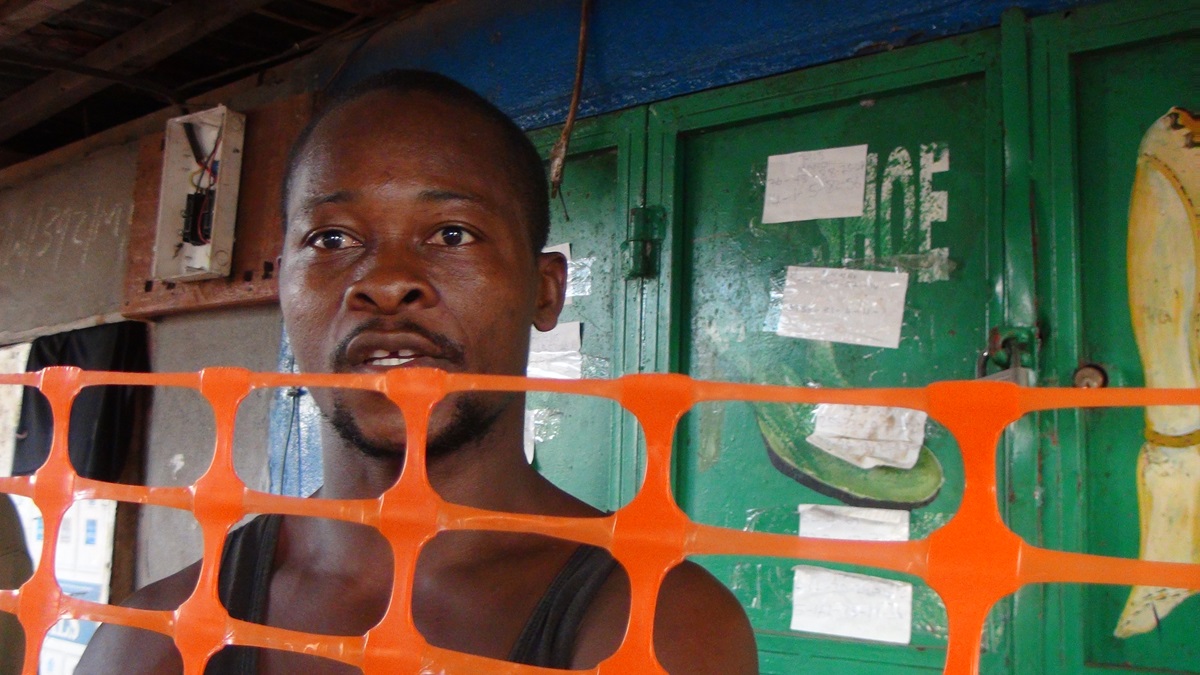   Joseph Bangura stands behind a barrier in a Freetown, Sierra Leone fish market. Bangura and hundreds of others are under quarantine after a boat with occupants infected with Ebola washed ashore at the market. Photo by Jan Snider, United Methodist Communications 