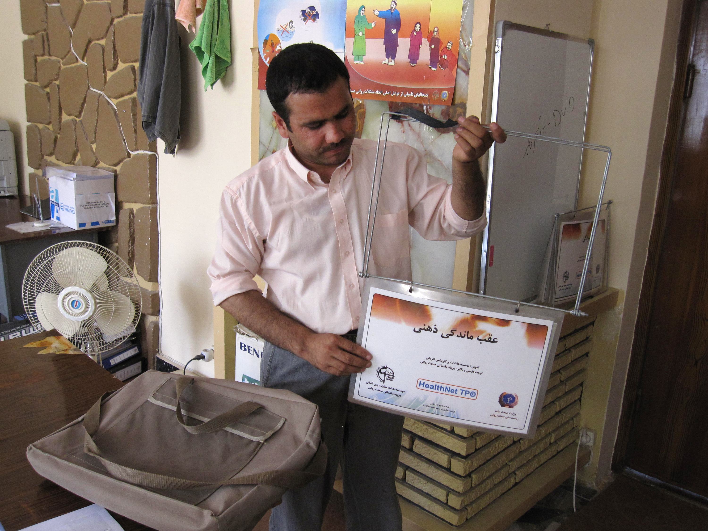 A trainer for a community mental health project in Afghanistan holds a flip chart used in the mental health awareness program for police, teachers, health care providers, mullahs and other community leaders.