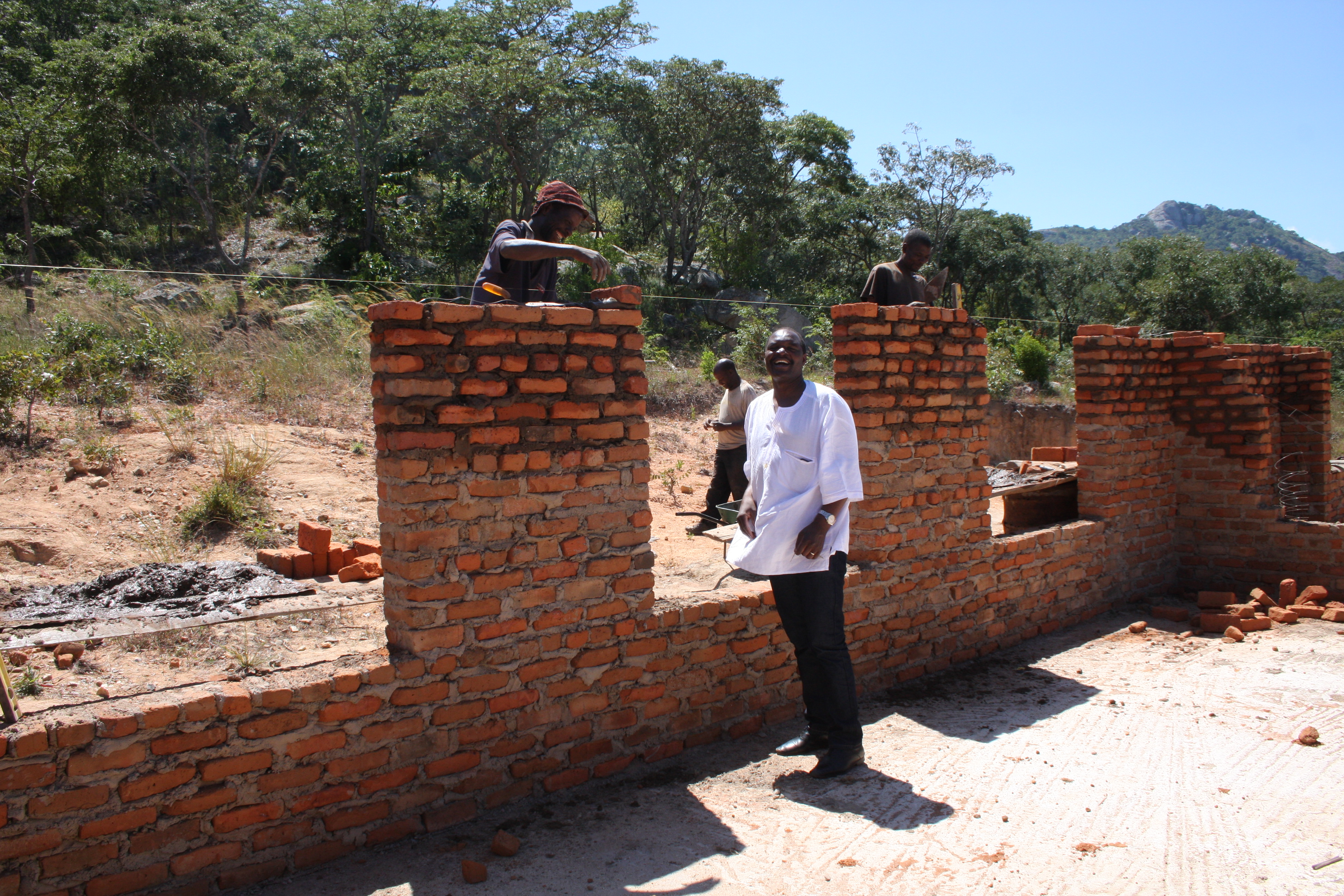 The Rev. Lloyd Nyarota chats with masons who are building walls for the new classrooms at Saungweme Primary School in Zimbabwe. Photo by Vicki Brown, UMNS