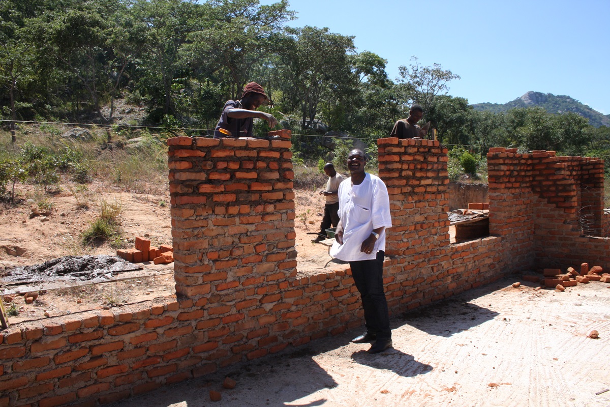 The Rev. Lloyd Nyarota chats with masons who are building walls for the new classrooms at Saungweme Primary School in Zimbabwe. Photo by Vicki Brown, UMNS