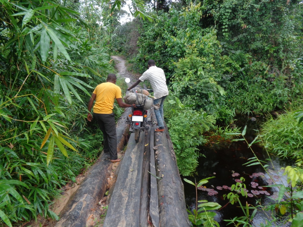 Alfred Zigbuo travels to various churches on a motorcycle. The team is walking the bike across a log bridge during a mission journey to Mutakuya Village, about 27 kilometers west of Kindu, Democratic Republic of Congo. Photo courtesy of Alfred Zigbuo
