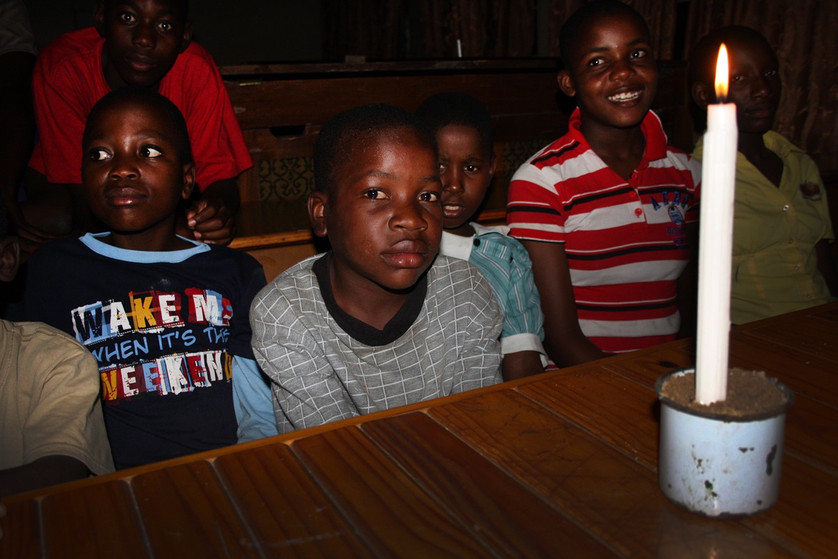 Boys at Home of Hope cluster around a candle during one of the frequent brownouts at The United Methodist Church’s Nyadire Mission in Zimbabwe. 