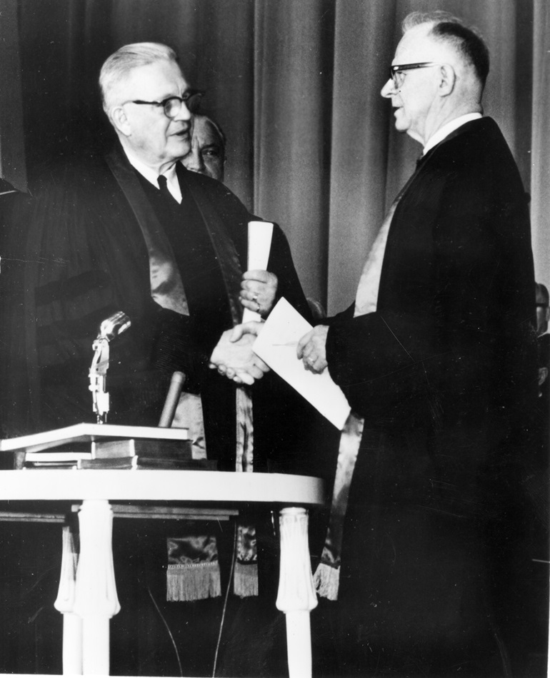 Evangelical United Brethren Church Bishop Reuben H. Mueller (left) and Methodist Bishop Lloyd C. Wicke join hands on April 23, 1968, symbolizing the merger between the two denominations.