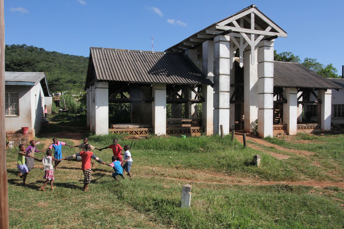 Children play a game in the farm area of Africa University, established by the 1988 United Methodist General Conference.  The building in the background was the original building where students gathered for breaks and outdoor dining in 1992. 