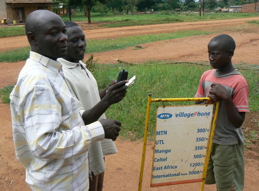 Men in Uganda use a mobile phone. Photo by Ken Banks, kiwanja.net.