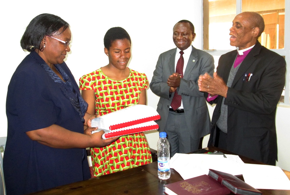 Laura and her mother receive a Braille hymnal in Shona from Bishop Eben Nhiwatiwa as the Rev.  Allan Gurupira looks on. Photo by Priscilla Muzerengwa, UMNS