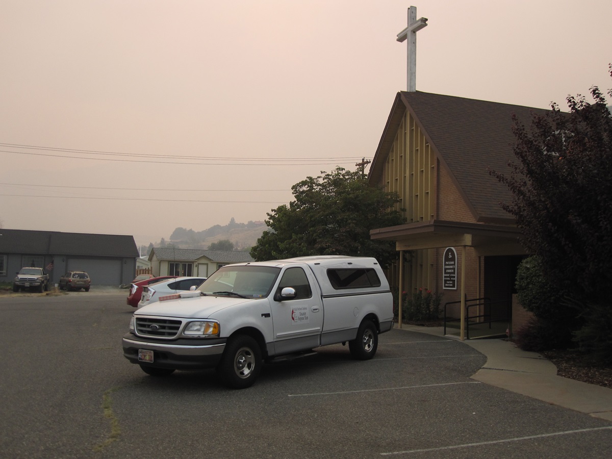 Smoke is evident  from the parking lot of Pateros Community United Methodist Church in Washington, which is serving as a shelter while wildfires rage in the area. The church itself was scorched and the parsonage burned to the ground by a wildfire a year ago. Photo by Jim Truitt