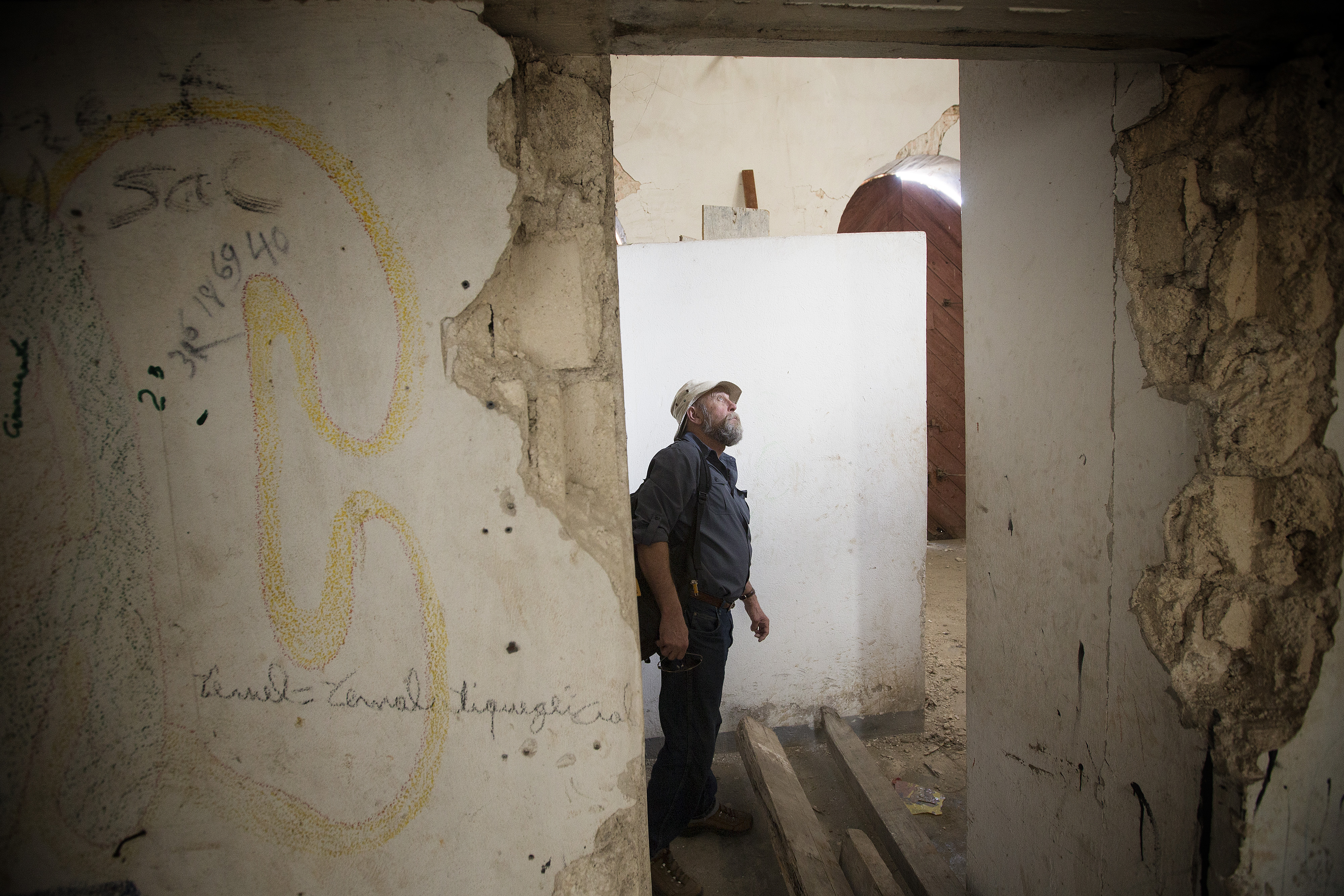 Warren McGuffin views damage remaining from the 2010 earthquake at the Methodist church in Petit-Goâve, Haiti. Several other buildings on the compound have been repaired. McGuffin is director of sustainability for the project. 2013 file photo by Mike DuBose, UMNS