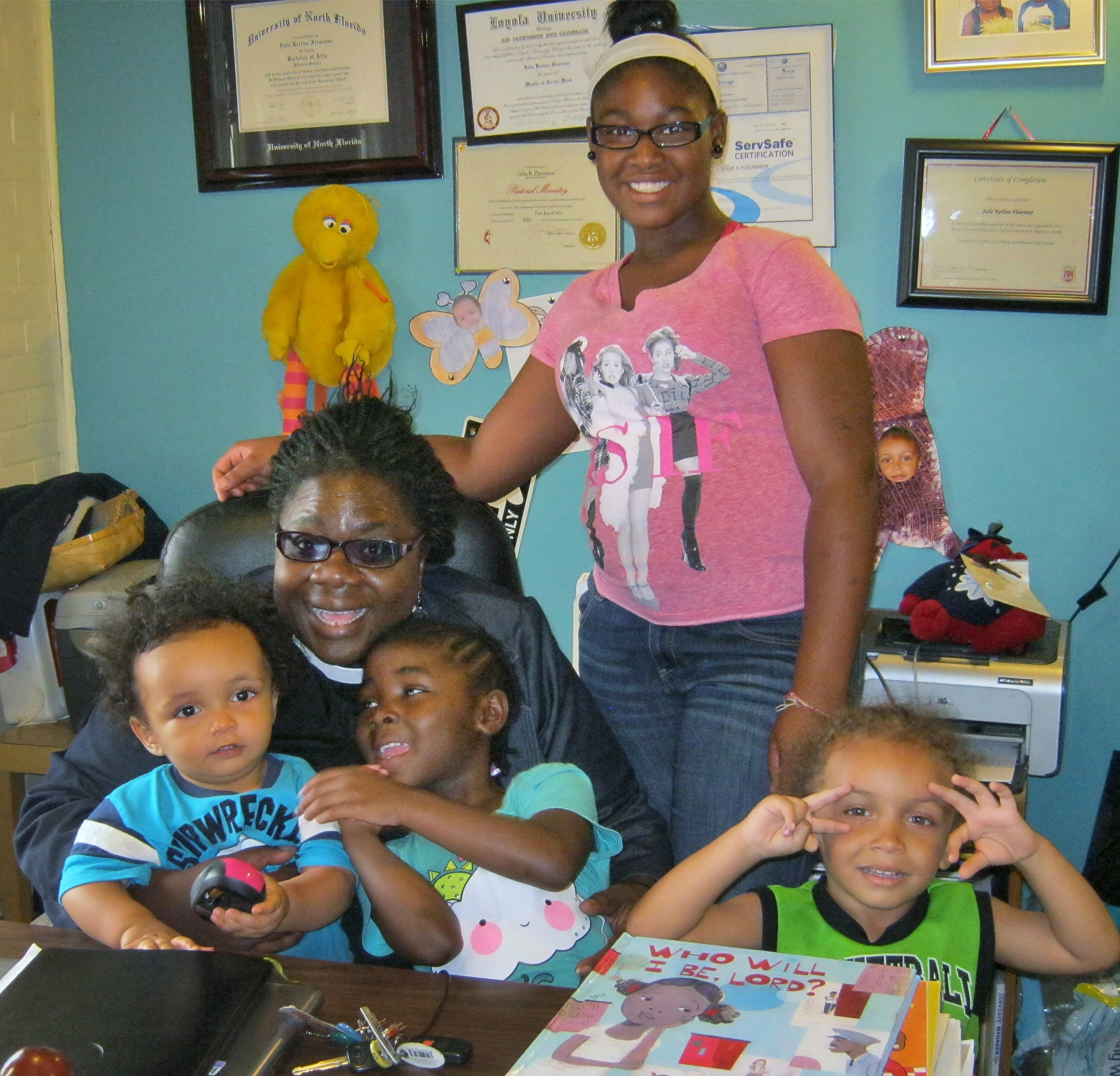 Photos of the children are mingled with the diplomas and awards on the wall of Rev. Julie K. Fleurinor's office in Resurrection United Methodist Church in Chicago.  From left, Jaron, Fleurinor, Eniyah, Erica and Cyrus. 