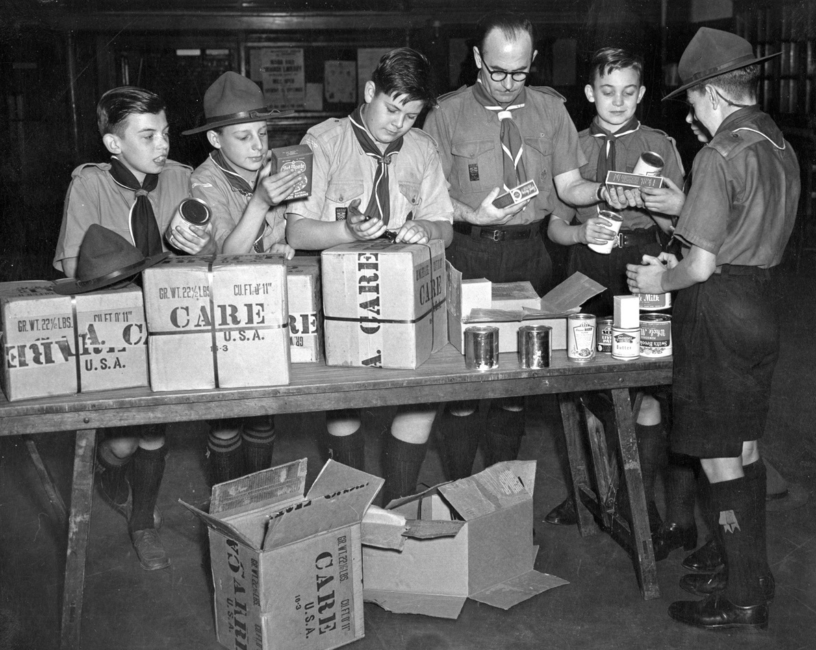 In 1948, U.S. Boy Scouts in Chicago sent five parcels of food through CARE to Boy Scouts in England. Pictured are J.M. Andrew, Scoutmaster and members of the Paddington Troop unpacking the parcels. After World War II, CARE distributed packages with food and other items to Europeans in need. Photo courtesy of CARE