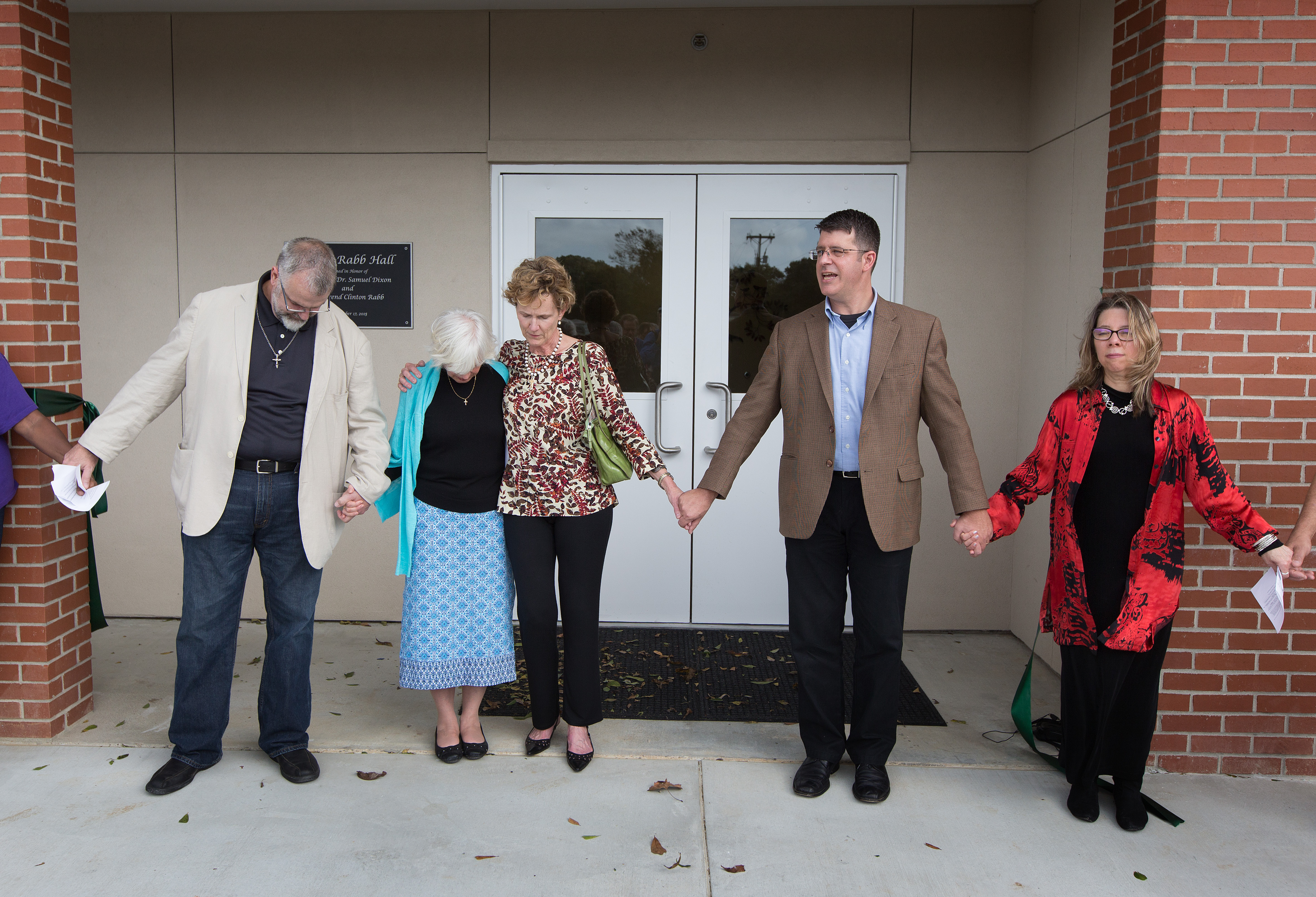 The Rev. John Cannon (second from right) leads the closing prayer during the dedication of Dixon Rabb Hall at the Sager Brown Depot in Baldwin, La. From left are: the Rev. Tom Hazelwood, former head of U.S. disaster response for UMCOR; Suzanne Rabb; Cindy Dixon; Cannon, superintendent of the church's Acadiana District; and the Rev. Denise Honeycutt, head of UMCOR. Photo by Mike DuBose, United Methodist Communications.
