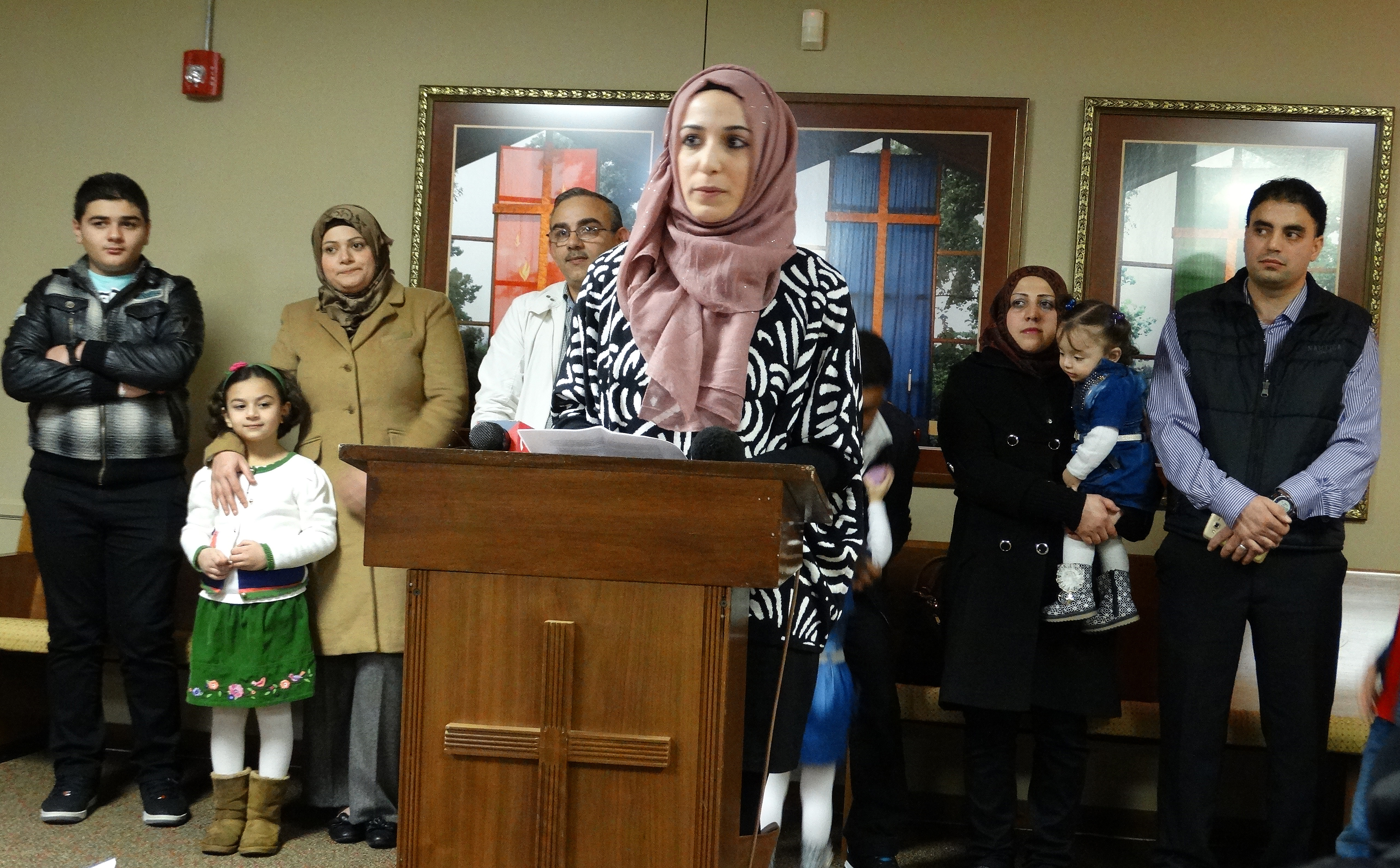 With three Syrian refugee families standing behind her, Nora Basha, with the Syrian American Council of Indiana, speaks during a press conference before a Dec. 11 rally and candlelight vigil in support of Syrian refugee families. The event was held by the council at Epworth United Methodist Church in Indianapolis. Photo by Dan Gangler, UMNS
