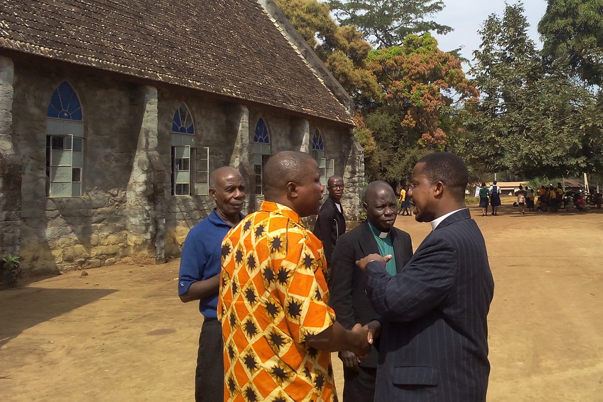 The Revs. David Tokpah (right) holds the hand of the Rev. Samuel Quire in conversation at the Gompa District Conference in Buchanan City, Nimba County, Liberia.