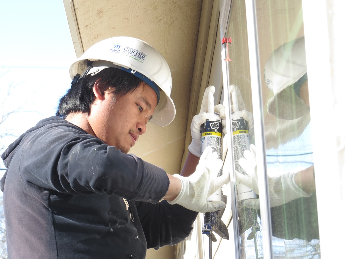 Eh Lay applies caulk as part of the 250 hours of “sweat equity” that goes with ownership of a Habitat for Humanity home. The Burmese refugee and his family will live in south Dallas, in the 100th Habitat home built by Highland Park United Methodist Church’s Carpenters for Christ. Photo by Sam Hodges, UMNS
 
