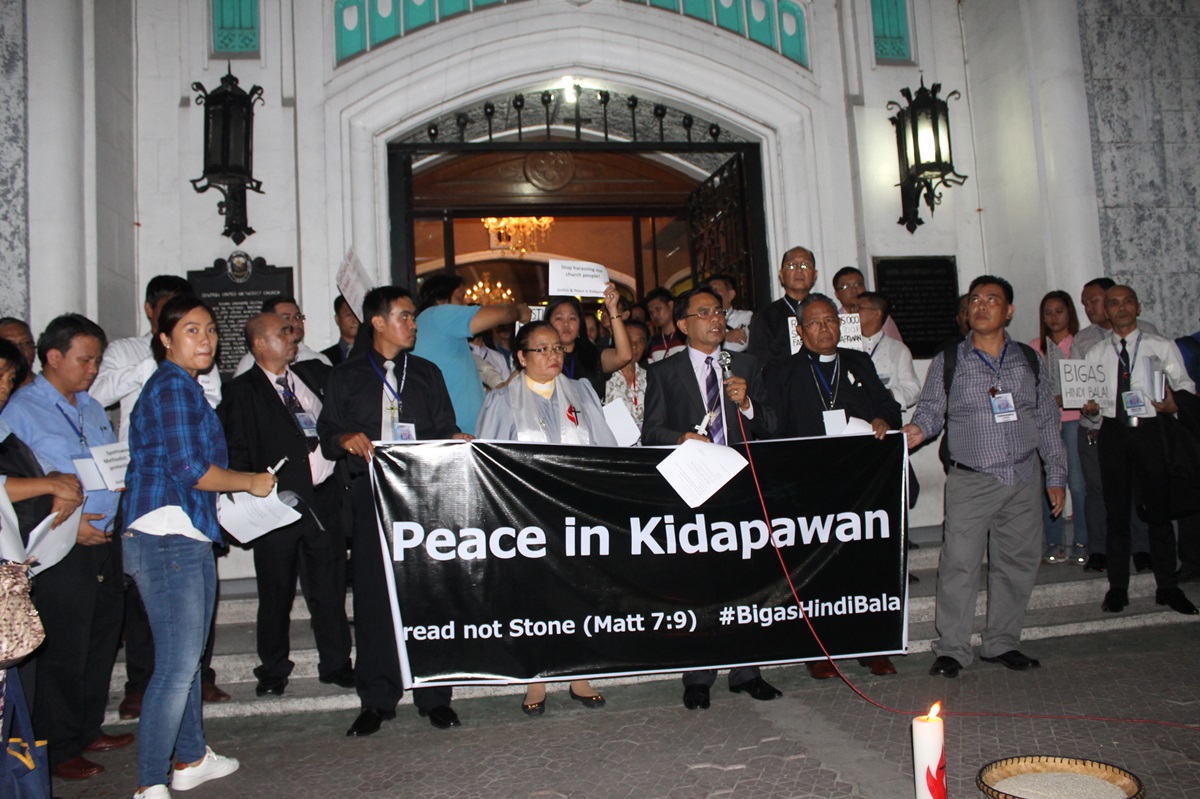 Bishop Rodolfo Juan, center, with the Rev. Rubynell Estrella, pastor of Central United Methodist Church in Manila, lead a candlelight prayer service at Central for farmers caught in a violent protest at the Spottswood United Methodist Church. 