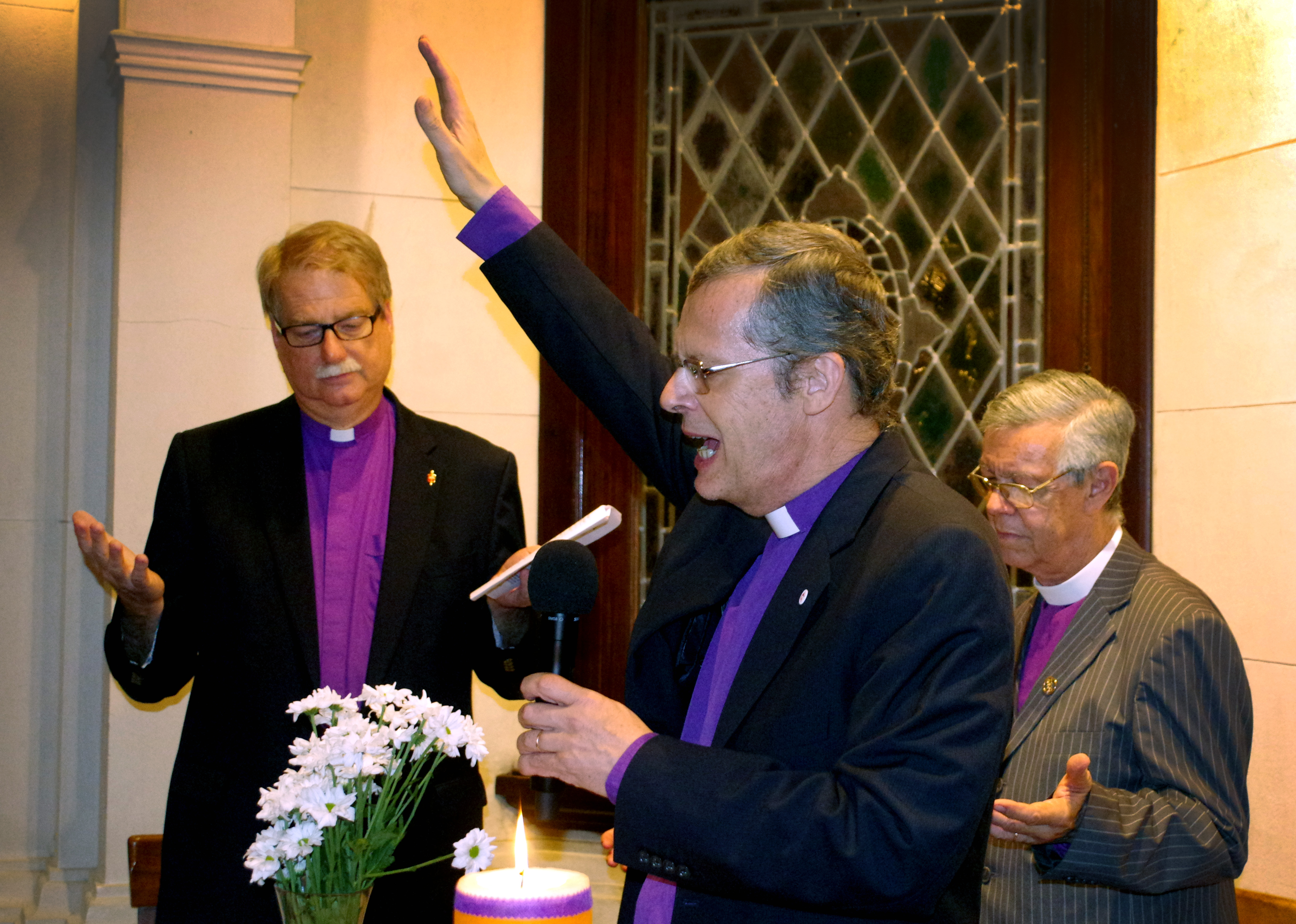 Bishop Frank de Nully Brown, who leads the Evangelical Methodist Church of Argentina, raises his handing in blessing during the dedication of the United Methodist Global Ministries and Upper Room regional office in Bueno Aires, Argentina. In the background (from left) are Florida Bishop Ken Carter and Bishop Stanley S. Moraes of the Methodist Church of Brazil. Photo by Gustavo Vasquez, UMNS