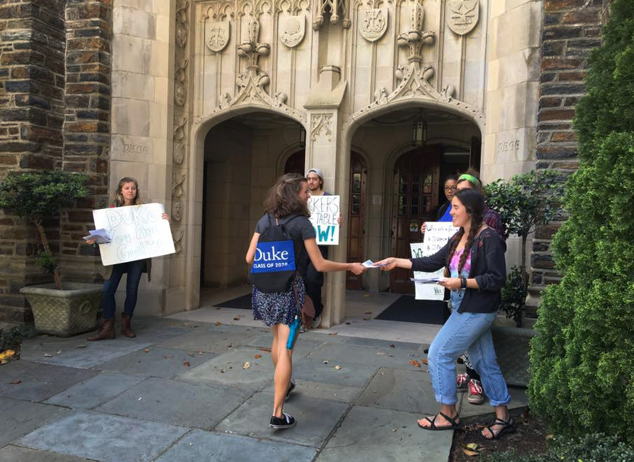 Students await visitors with signs outside Page Auditorium on the campus of Duke University.