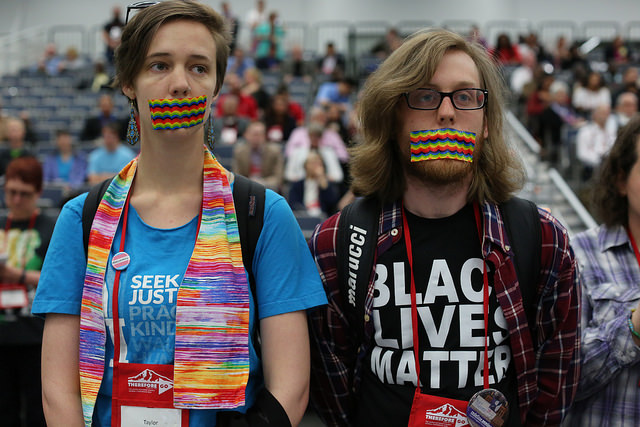 United Methodists in support for LGBTQ community in the church ask for an apology when Dorothee Benz from the New York Conference was called out of order during discussion of Rule 44 at the 2016 United Methodist General Conference in Portland, Ore. Standing with their mouths taped are (from left) Taylor Gould from the Iowa Conference and Sean Crews from the Oklahoma Conference. Photo by Kathleen Barry, UMNS