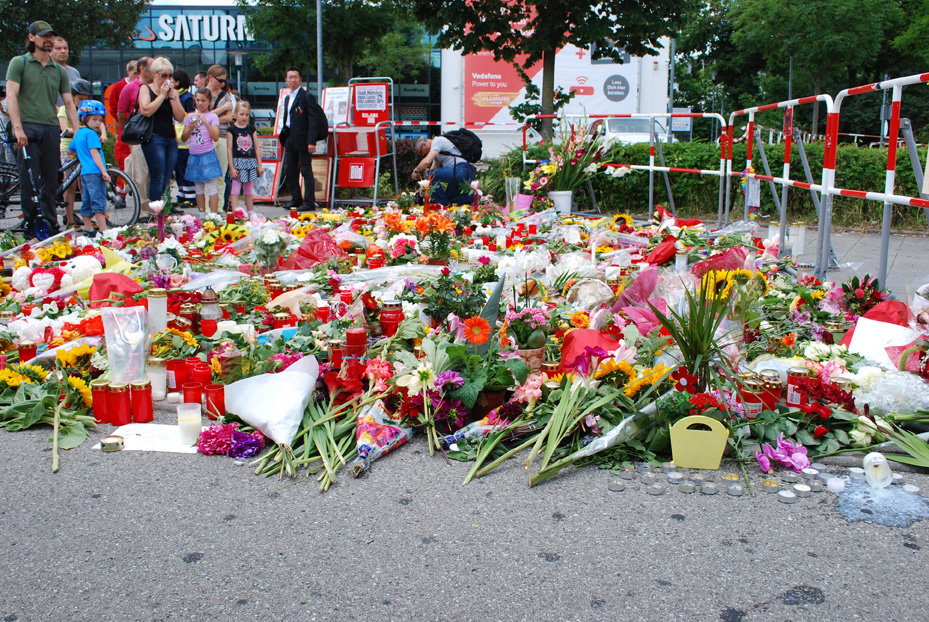 People stop alongside a makeshift memorial to victims of the July 22 Olympia Mall shooting in Munich that killed nine and left 27 injured. Photo © Volker Kiemle 