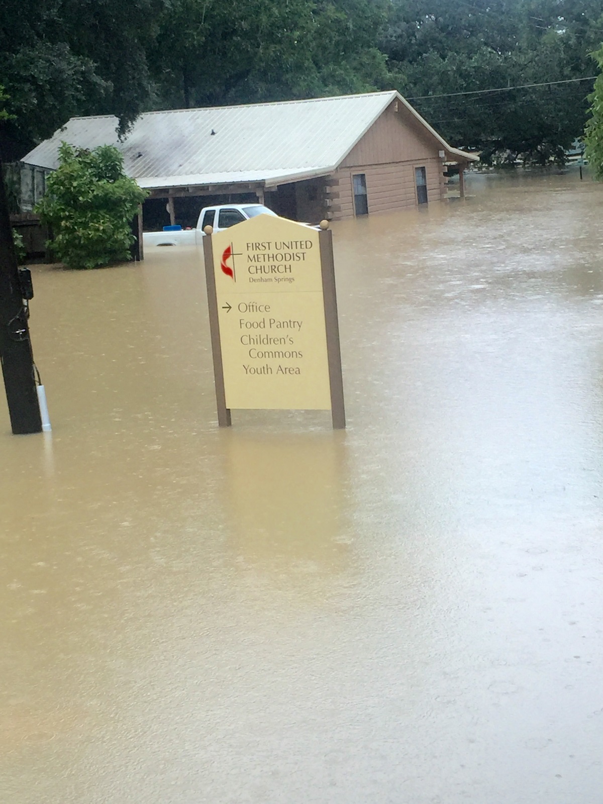 Recent flooding in Denham Springs, Louisiana, at one point nearly covered a sign for the First United Methodist Church there. The home in the background belongs to a member of that church. Photo courtesy of the Rev. Jackie King