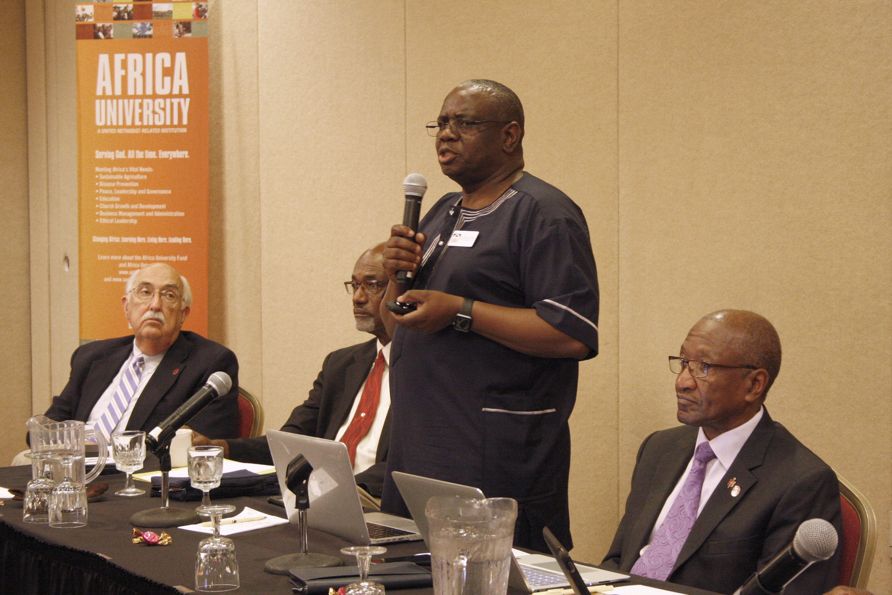 Munashe Furusa, vice chancellor of Africa University, said the United Methodist university is open and operating smoothly despite political unrest in Zimbabwe, although some students have been unable to register for financial reasons. Retired Bishops J. Lawrence McClesky (left) and Ernest Lyght (middle left) and Marcus Matthews (right) listen to Furusa’s report. Photo by Vicki Brown, UMNS.