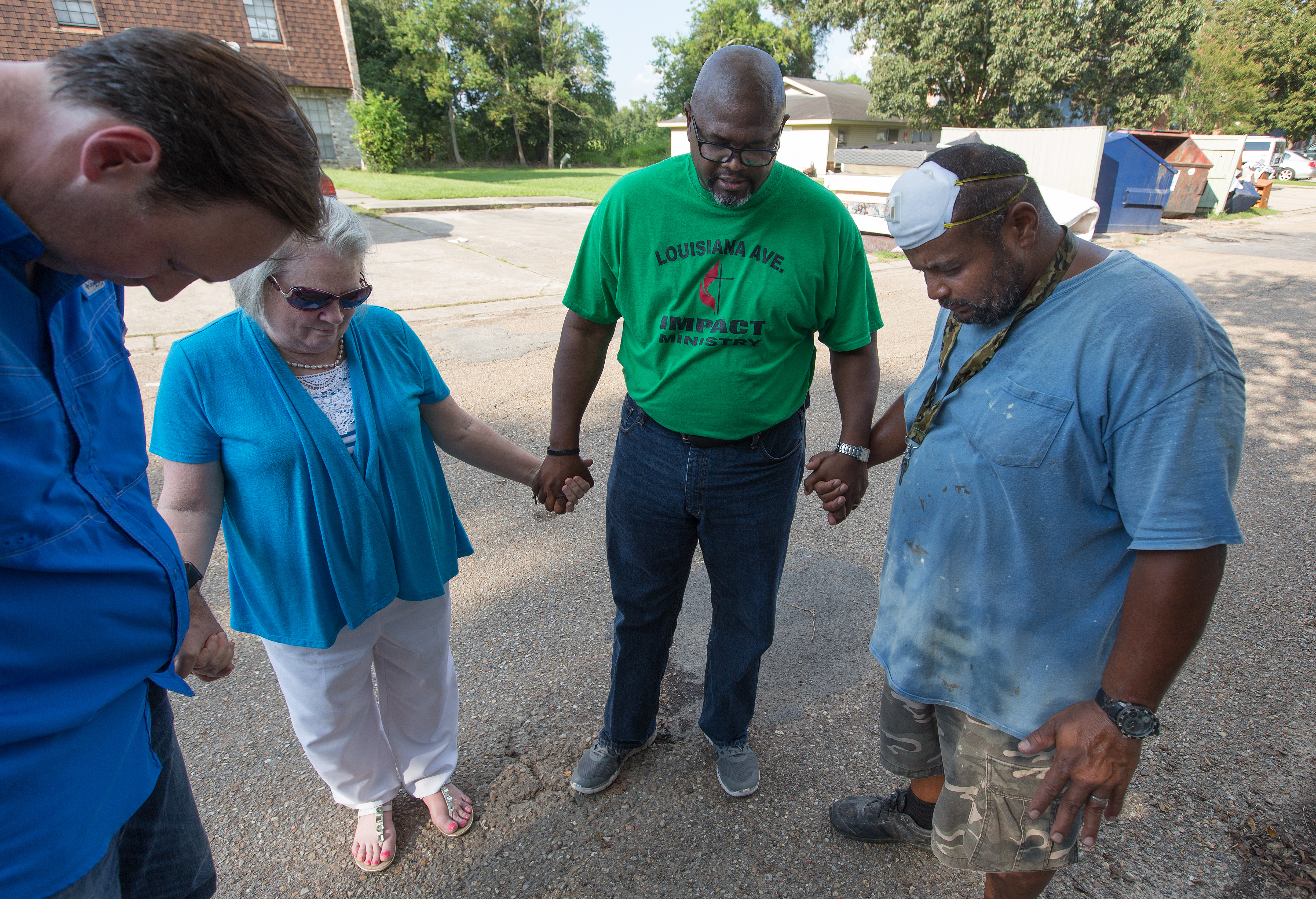 The Rev. Robert Johnson (second from right) leads a prayer with maintenance worker Kevin Oliver (right) at a flood-damaged apartment complex in Duson, La. Praying with him are the Revs. Todd Rossnagel (left) and Susan Ferguson. 