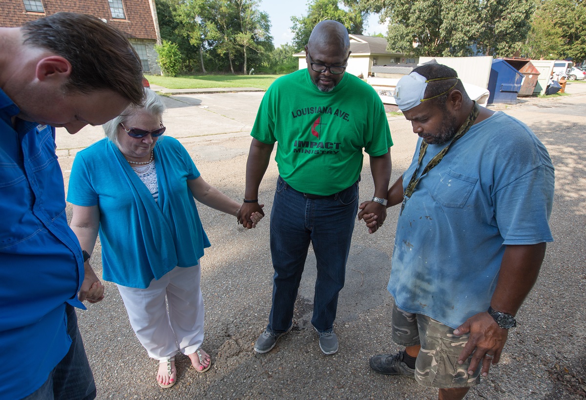 The Rev. Robert Johnson (second from right) leads a prayer with maintenance worker Kevin Oliver (right) at a flood-damaged apartment complex in Duson, La. Praying with him are the Revs. Todd Rossnagel (left) and Susan Ferguson. 
