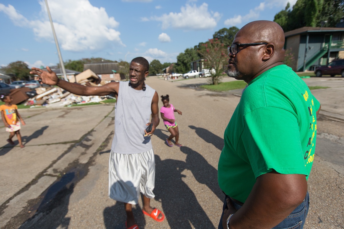 The Rev. Robert Johnson (right) visits with Ronald Redmond and his children while checking on the welfare of residents at a flood-damaged apartment complex in Duson, La. Johnson is pastor of Louisiana Avenue United Methodist Church in Lafayette. 