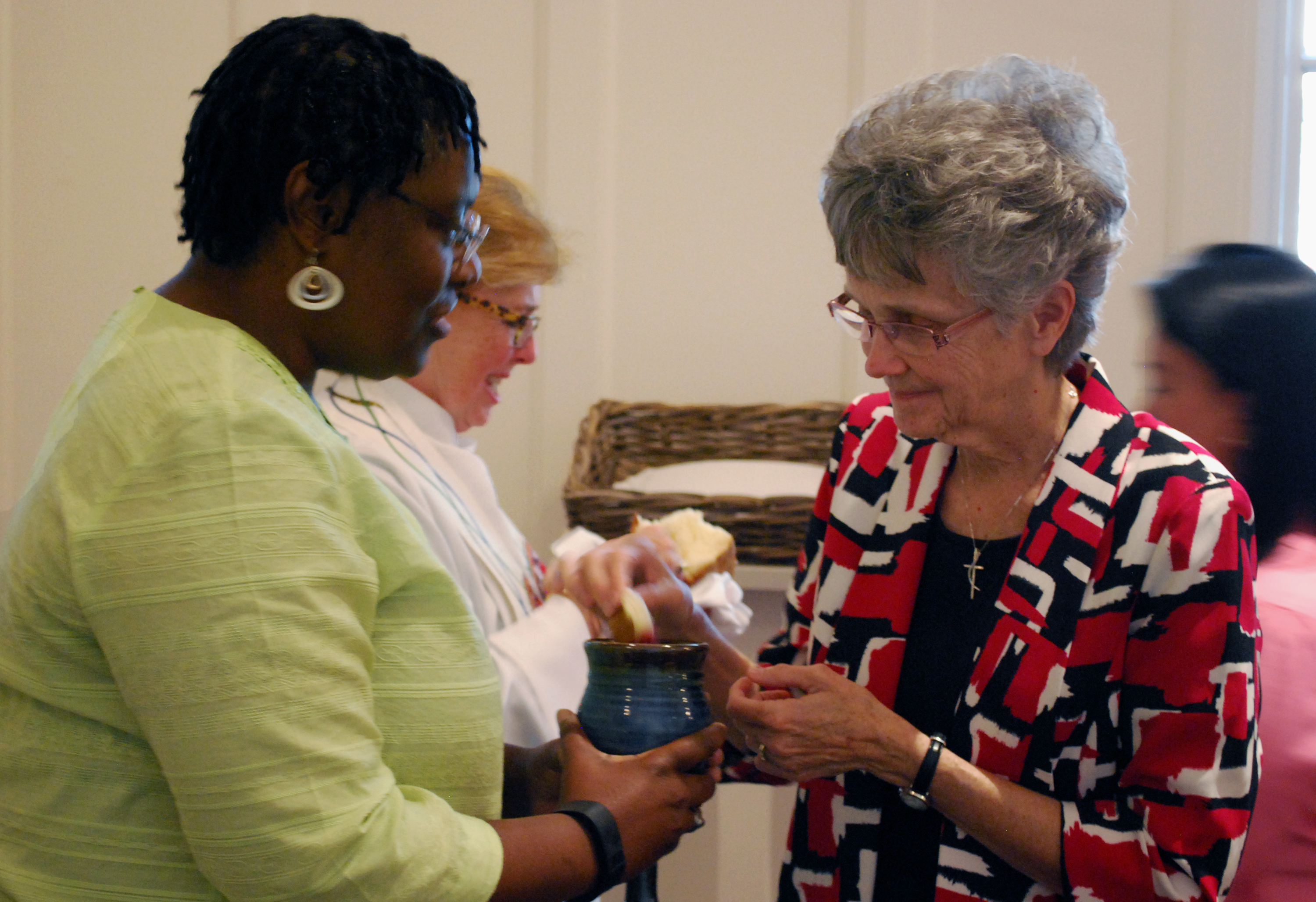 The Rev. Tamara Brown, a director from the Kentucky Conference, serves communion to Philadelphia Area Bishop Peggy Johnson, a fellow director, during the closing worship service of the Sept. 21-24, 2016 meeting of the United Methodist Board of Church and Society. 