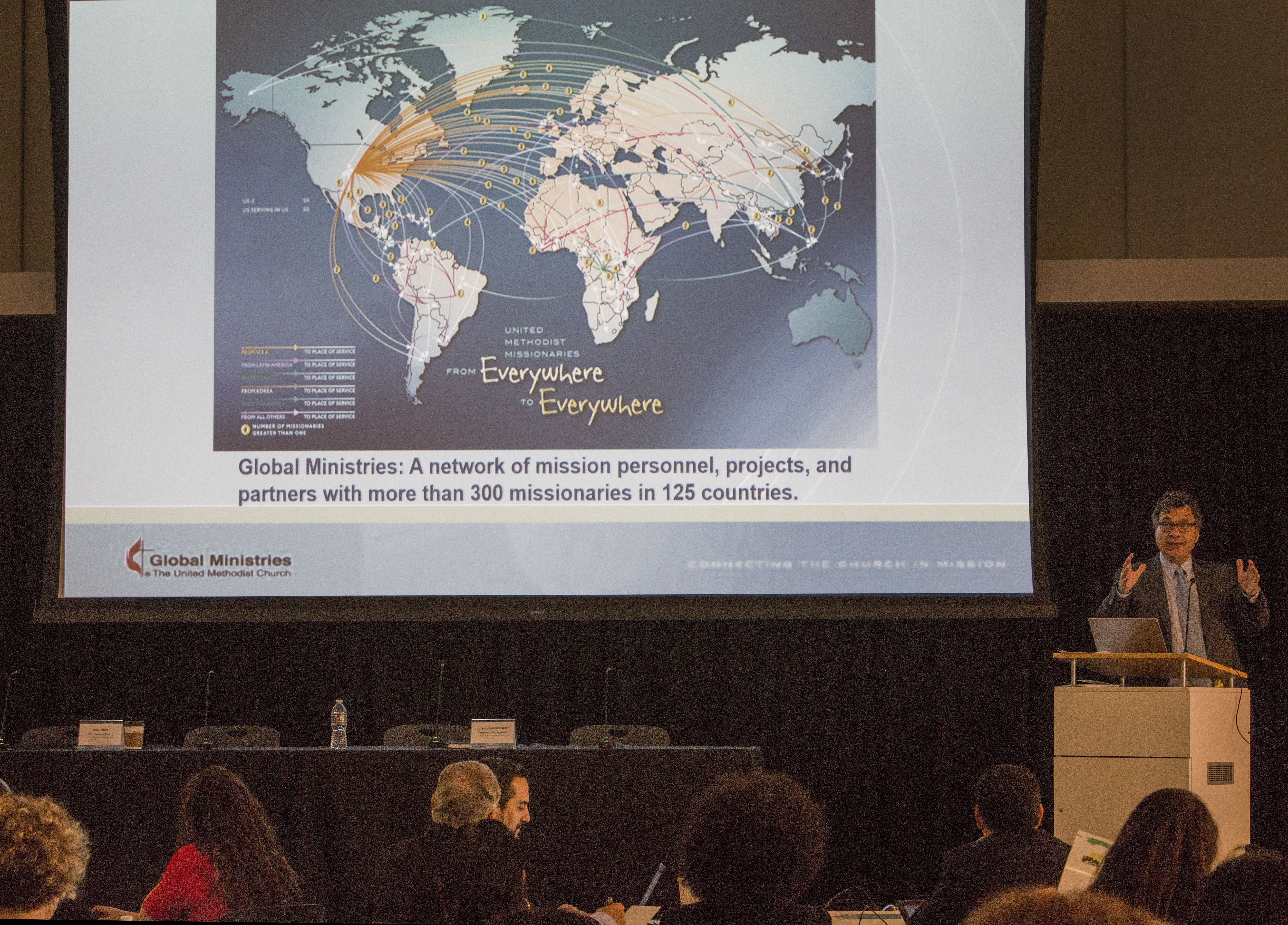 Thomas Kemper delivers his address with the map showing the locations of United Methodist missionaries around the world. 
