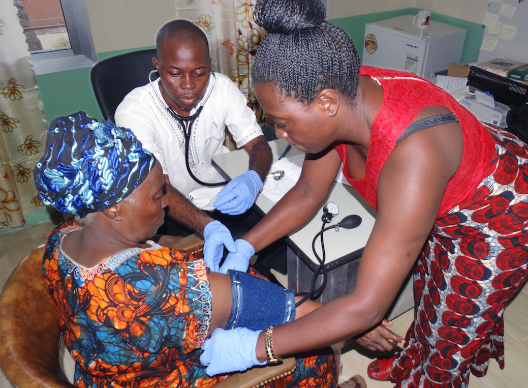 Dr. Omar Lamin examines a hypertension patient in his office at United Methodist Kissy Hospital in Freetown. Photo by Phileas Jusu, UMNS.