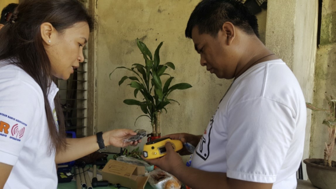 Pastor Jucar Tabunan (right) receives a Freeplay solar radio from April Mercado as part of the 2016 Typhoon Haima disaster response. Photo courtesy of April Mercado, United Methodist Communications. 
