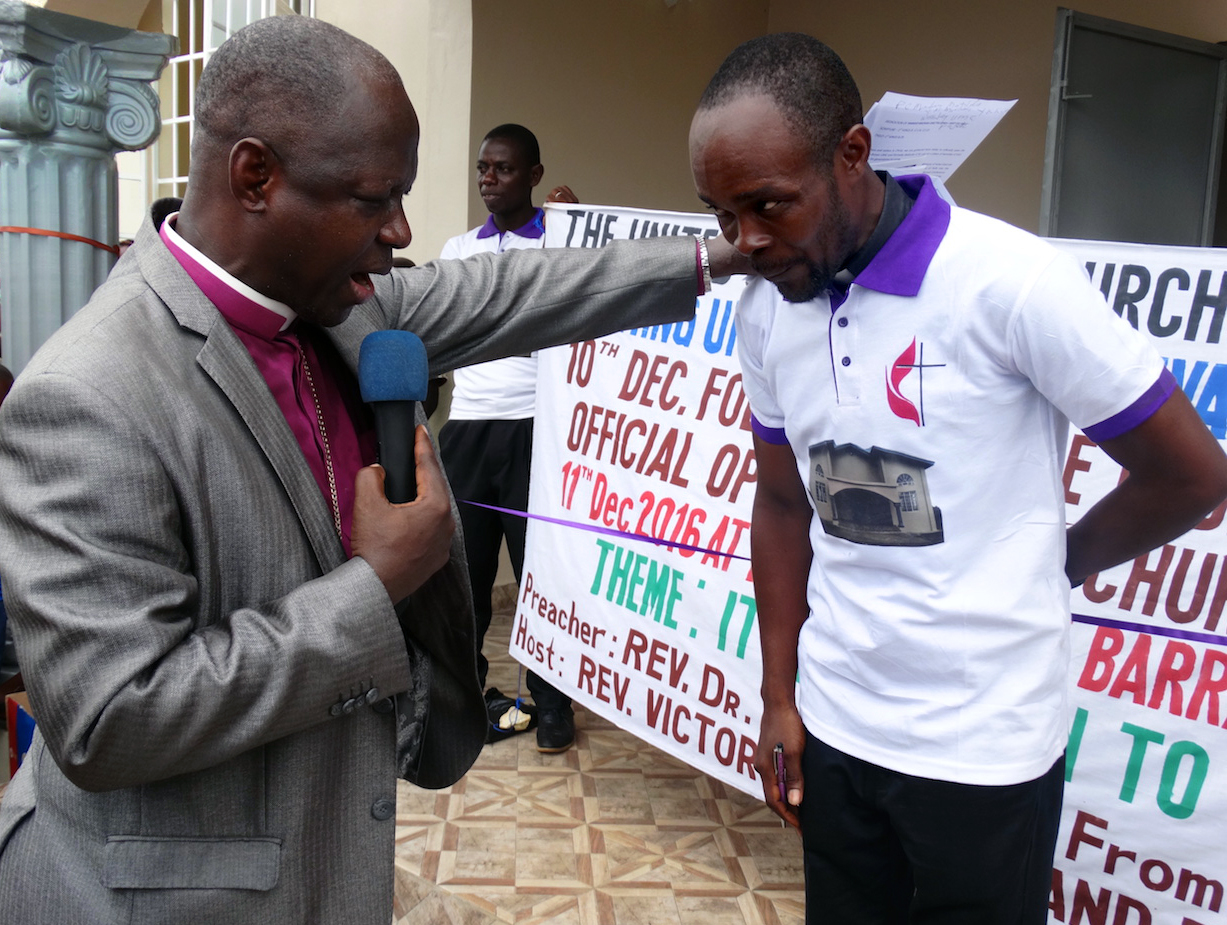 Bishop John Yambasu prays for the Rev. Victor Kainboy for his leadership of the new church in Pujehun. Photo by Phileas Jusu, UMNS.