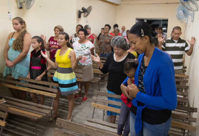 Parishioners stand to pray during worship at A Place of Hope Methodist Church, a converted auto repair shop, in Santa Clara. Photo by Mike DuBose, UMNS.