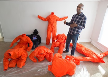 Ndume Olatushani, a death row exonoree, is one of the artists whose work is included in Stations of the Cross opening in Washington during Lent. Using chicken wire, Olatushani molds the jumpsuits into prisoners bowed and writhing in agony from being confined. Photo by Mike DuBose, UMNS. Ndume Olatushani, a death row exonoree, is one of the artists whose work is included in Stations of the Cross opening in Washington during Lent. Using chicken wire, Olatushani molds the jumpsuits into prisoners bowed and writhing in agony from being confined. Photo by Mike DuBose, UMNS.