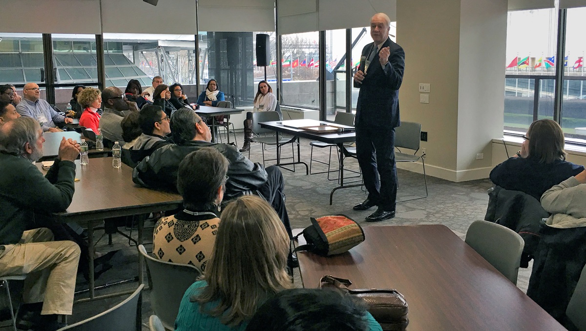 New York Area Bishop Thomas Bickerton brings greetings to directors of the United Methodist Board of Church and Society during their March 24 meeting at the Church Center for the United Nations. The flags flying outside the United Nations, across the street, are visible through the windows of the second-floor conference room. Photo by Levi Bautista, GBCS