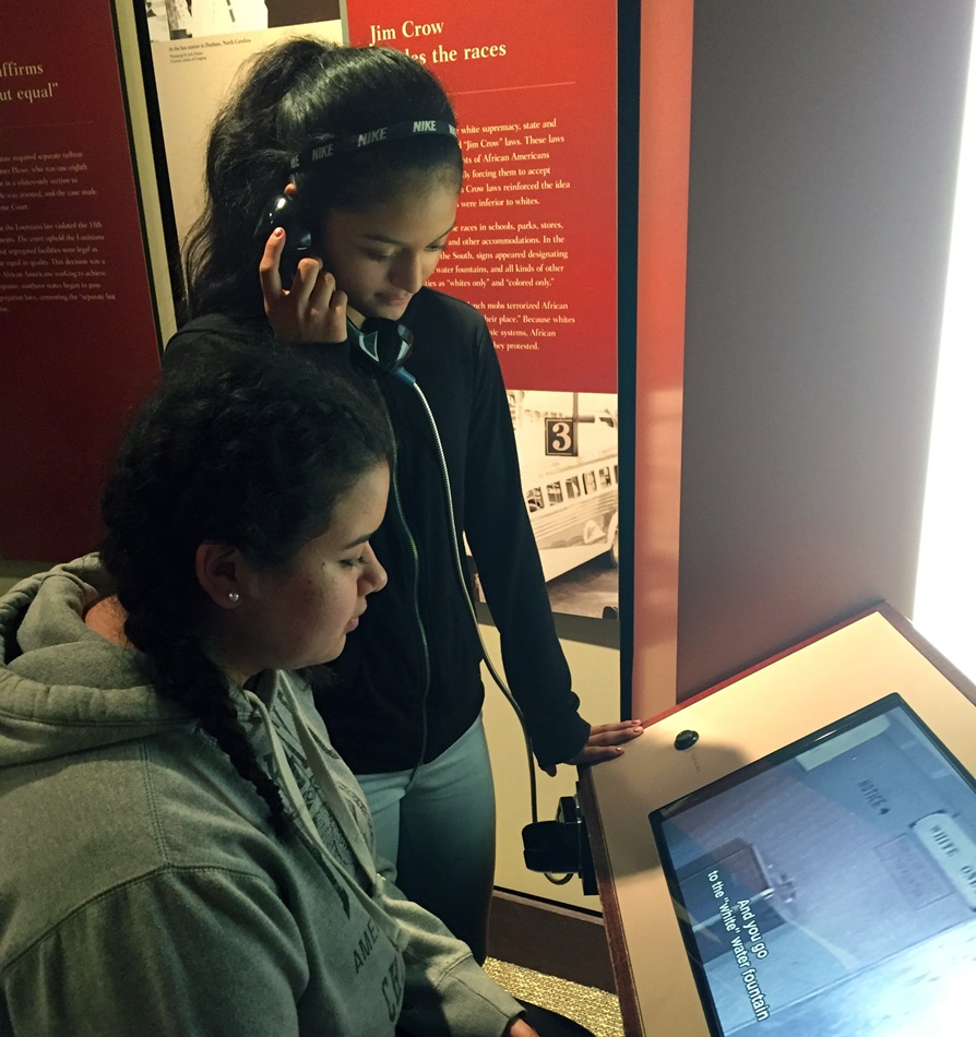 Janel Sarabia (seated) and Aili Martinez take in an exhibit at the Central High School National Historic Site in Little Rock, Ark. They were part of a group of Hispanic youth from Dallas who toured civil rights sites March 11-14, thanks to a grant from the United Methodist Church’s National Plan for Hispanic/Latino Ministry. Photo by Amy Spaur.