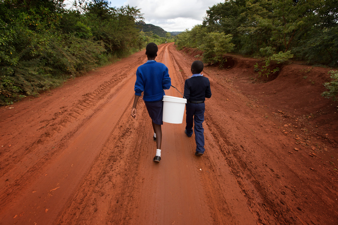 Emelly Maringire, 14, (left) and Malvin Musengwa, 13, walk to fetch water at the end of their school day at Chirichoga High School. Photo by Mike DuBose, UMNS.