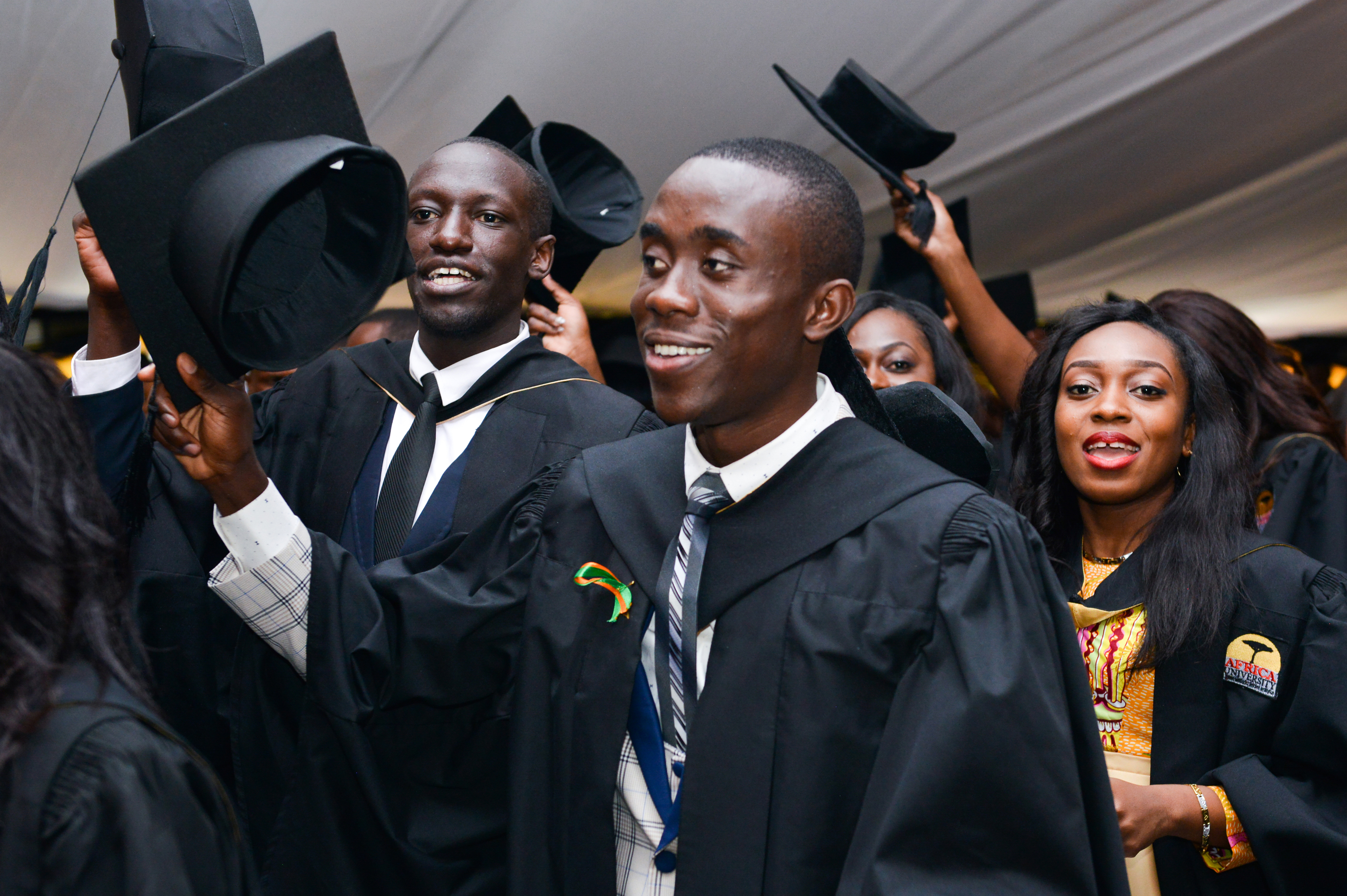 Odilon Mwaba (center) and Tikky Giorgio Olang’o (left) raise their caps in celebration at Africa University’s 2017 commencement. More than 700 students from 23 African countries graduated from the United Methodist university in Mutare, Zimbabwe. Photo courtesy of Africa University.